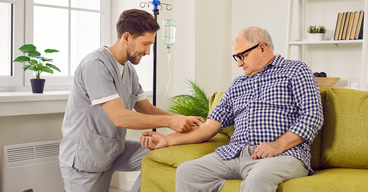 Nurse assisting elderly man with IV treatment.